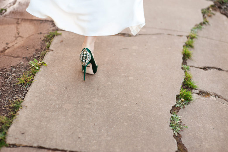 View of bride's dark green, bejeweled shoe, walking away on paved path