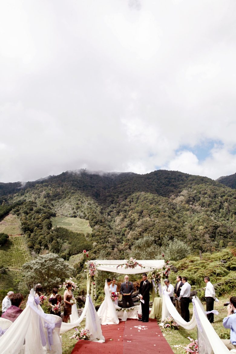 outdoor wedding ceremony under canopy, at base of green mountain