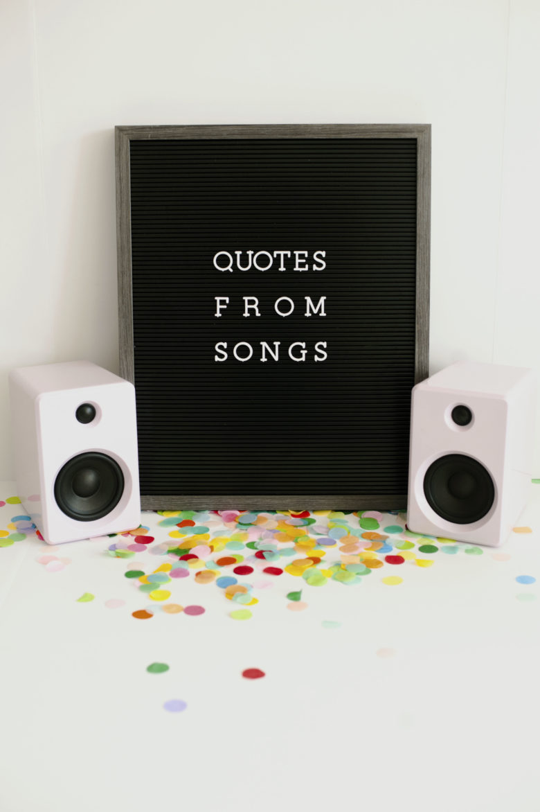 black board that says quotes from songs next to speakers and confetti