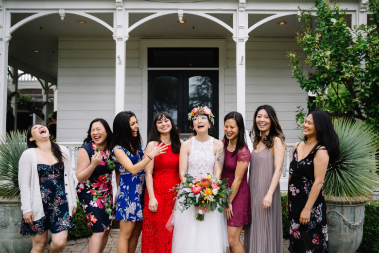 A bride laughing happily as she is surrounded by her amazing wedding party