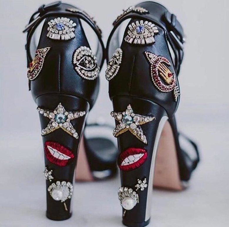 Black high-heeled shoes covered in bedazzled patches 