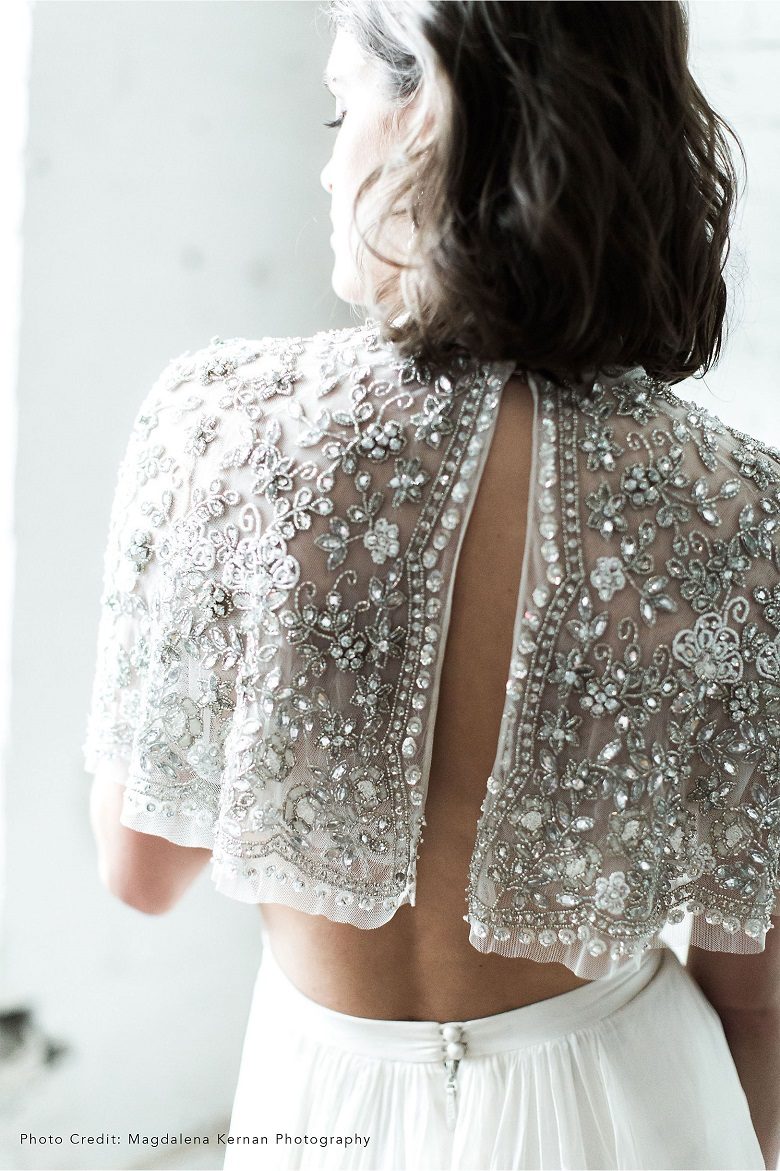 View of a bride's upper back, showing off her half length sparkly cape