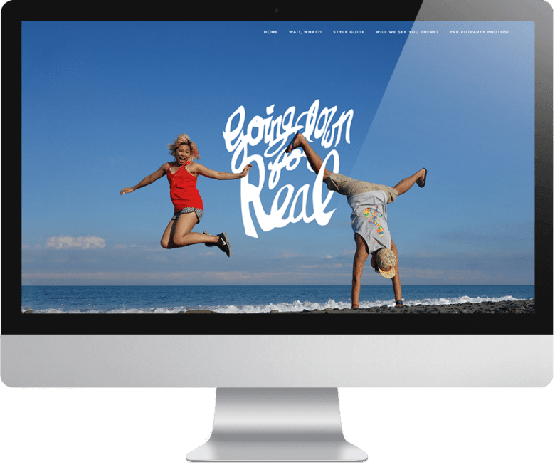Wedding website: Woman in red shirt jumping with joy, man in cap doing a wide-legged handstand on the beach near the water with text overlay that reads "going down for real" on computer monitor