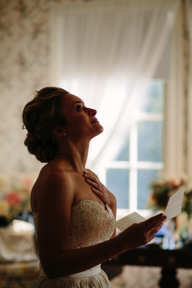 bride emotionally moved by letter she is reading, looking up, clasping hand to heart