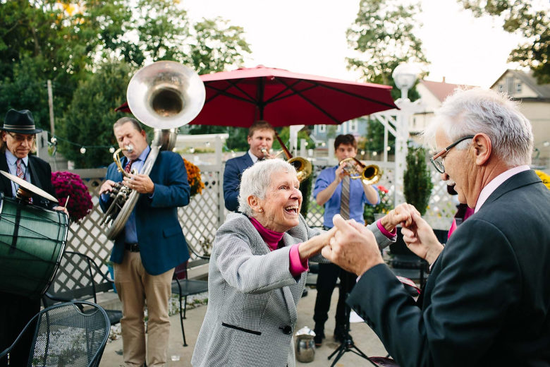 elderly couple dancing outside as brass band plays behind them