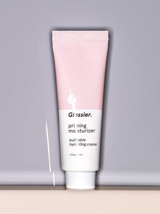 Pink and white tube of Glossier priming moisturizer on gray background