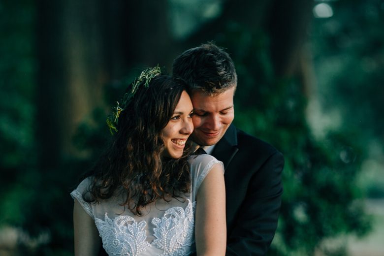 A Wedding Couple hold each other in a forest.