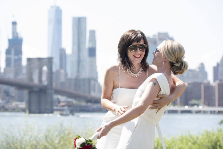 brides kissing in front of Brooklyn Bridge