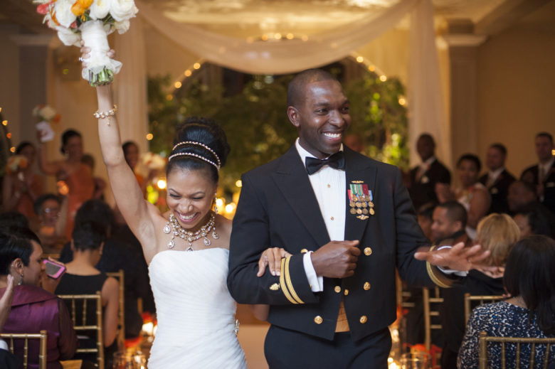 bride raising bouquet and groom in military dinner dress uniform recessing down the aisle
