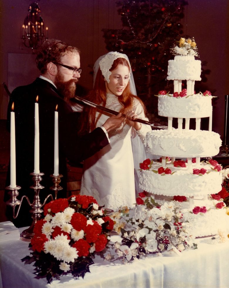 a couple cutting their wedding cake with a sabre