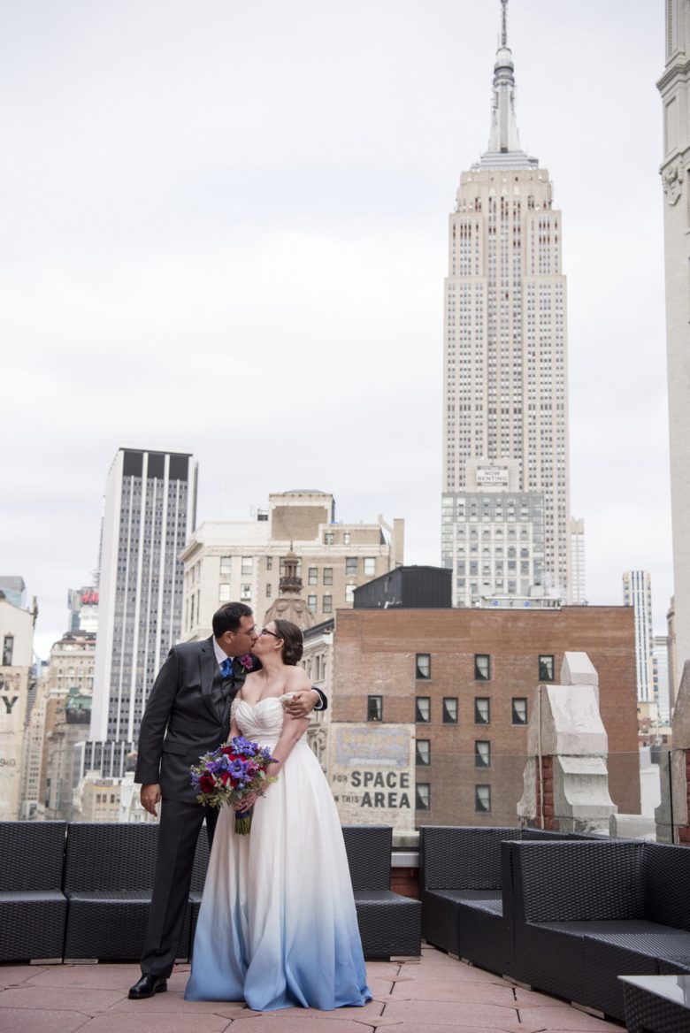 bride in blue dress and groom kissing in front of Empire State Building