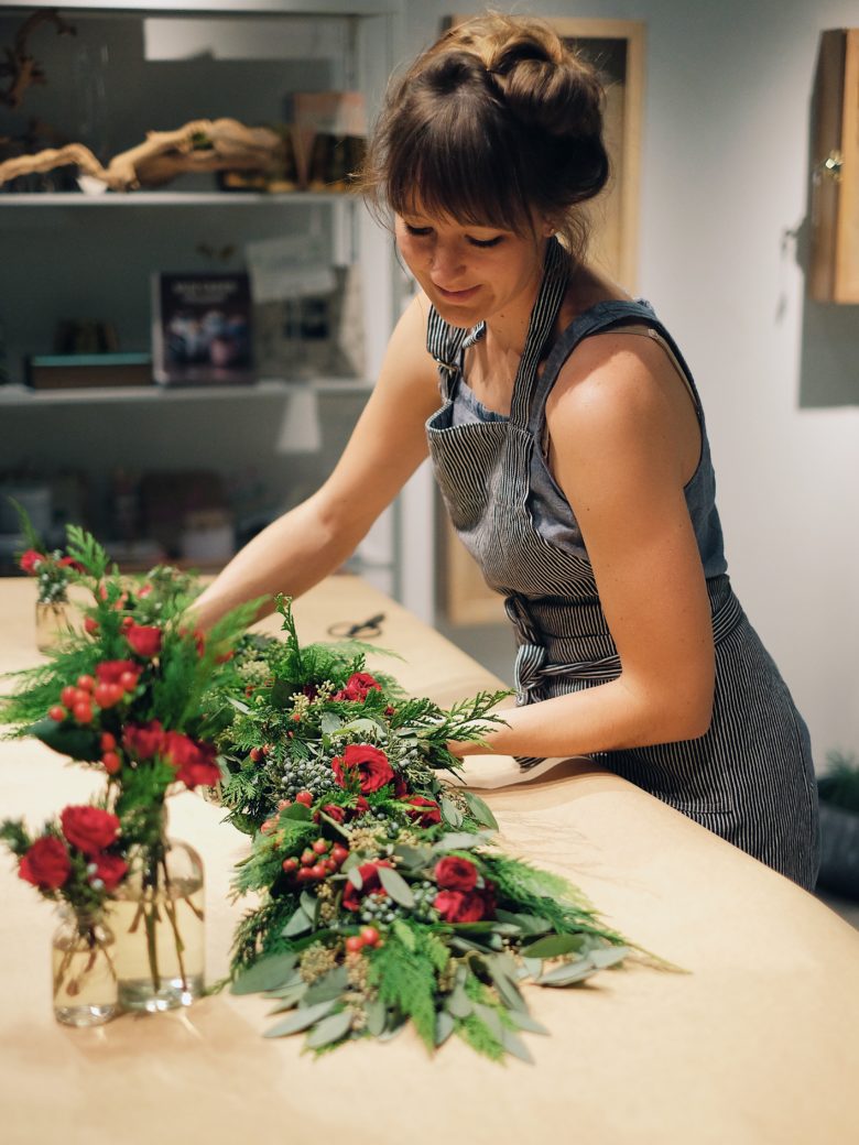 woman arranging red, green, and white garland in workshop