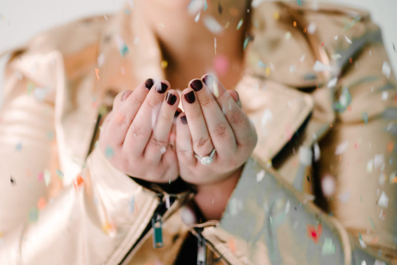hands cupped together, catching confetti wearing engagement ring
