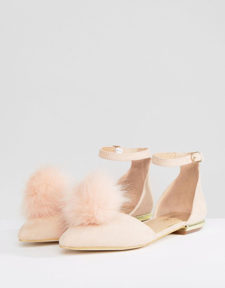 a pair of flats with a peach/pink pom 