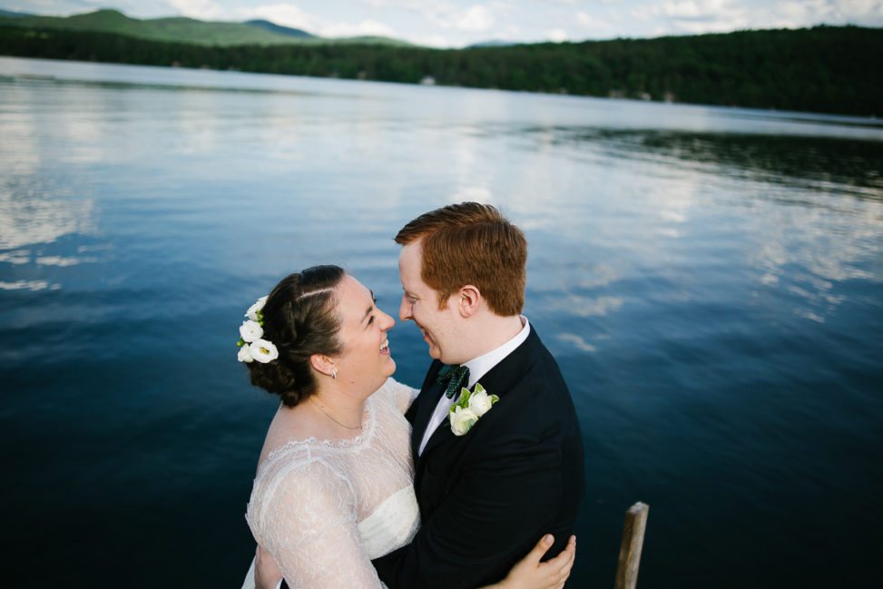 bride and groom embracing in front of a lake