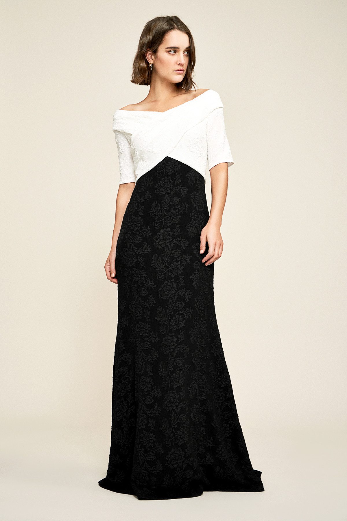 Short haired brunette model posing in elegant white and black contrast crossover bodice Tadashi Shoji gown
