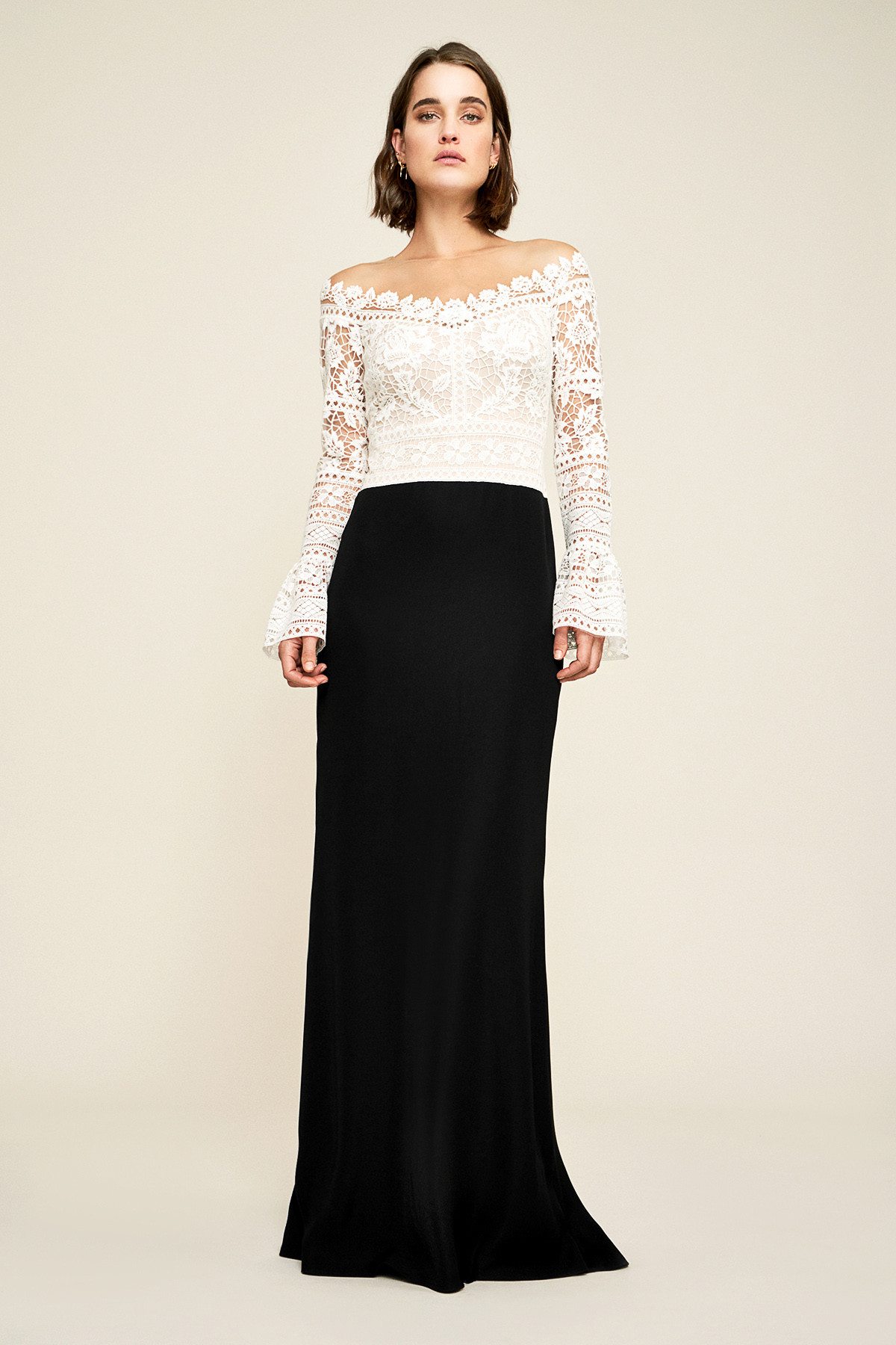 Short haired brunette model posing in delicate white peasant lace sleeves and black skirt Tadashi Shoji gown