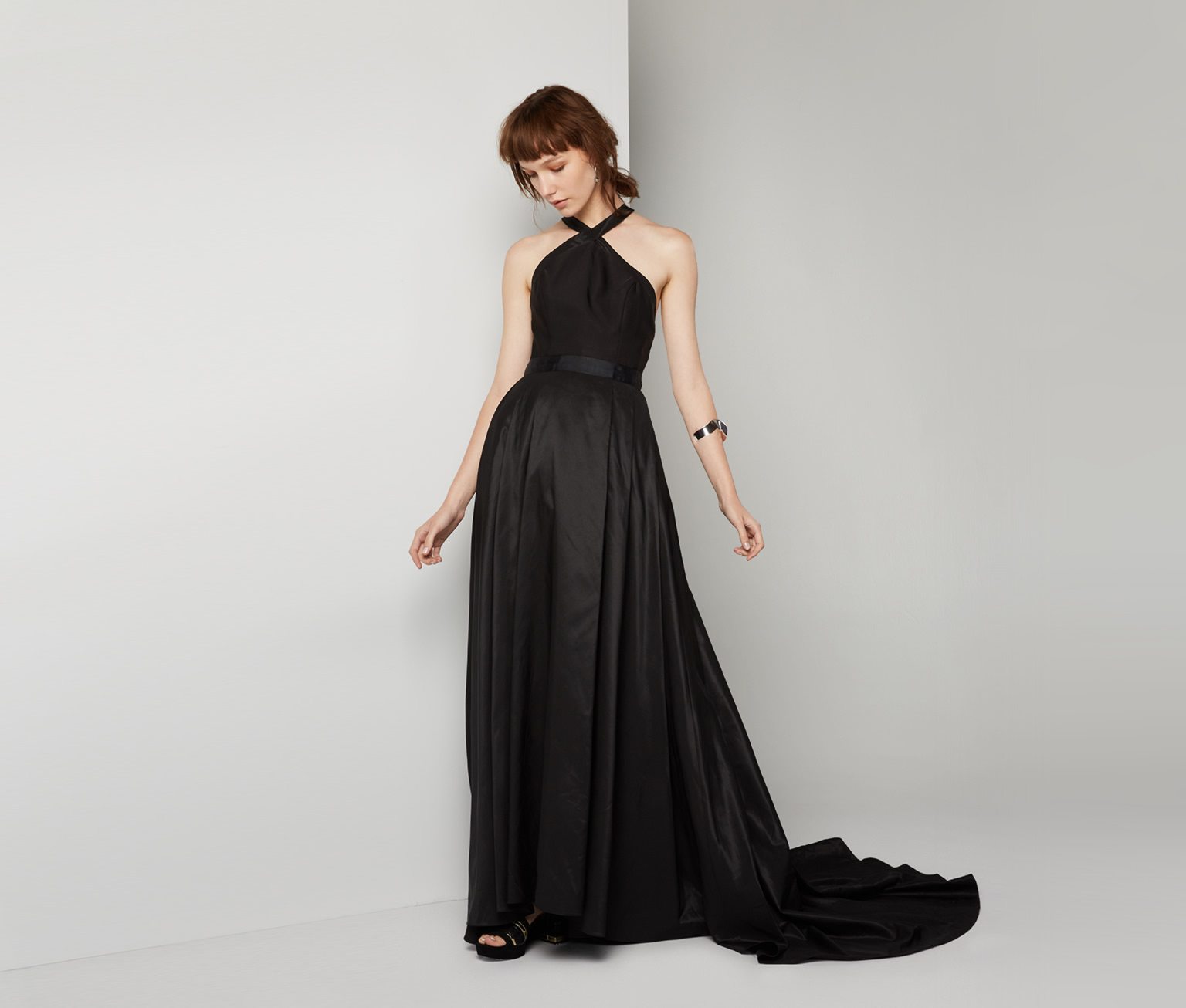 Model posing in black halter gown with train 