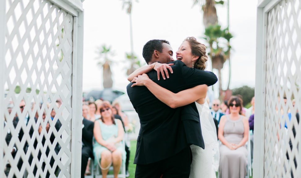 A wedding couple embrace and laugh at the end of their ceremony