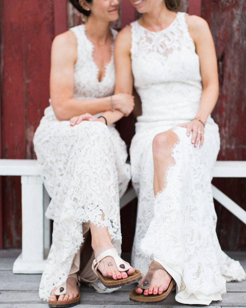 two brides sit next to each other, smiling on their wedding day
