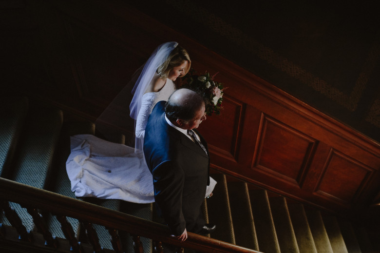 A bride walks down stairs with her father - wedding songs