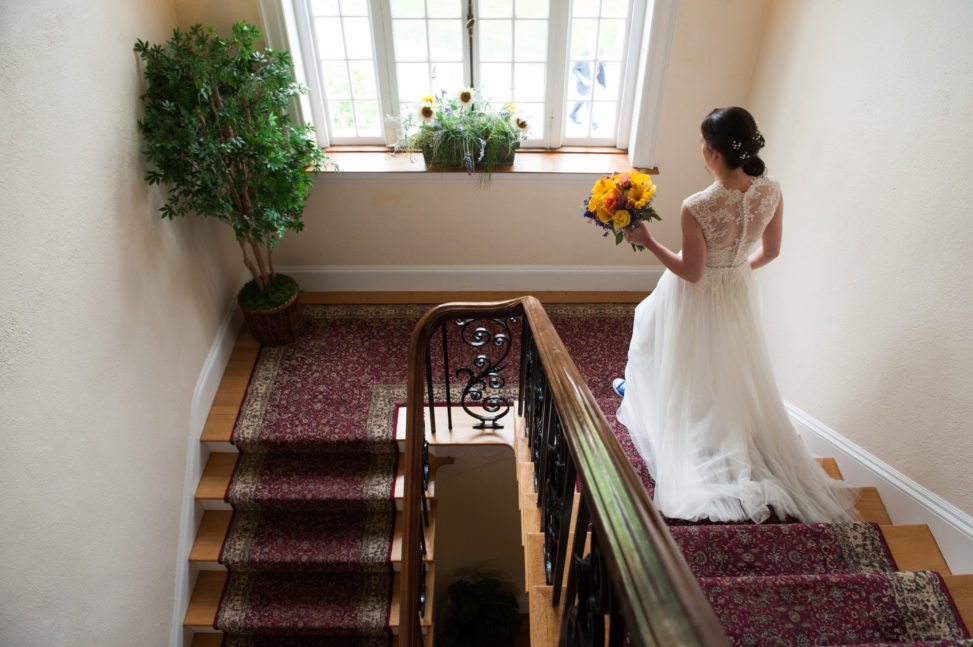 a bride walks down a staircase holding her bouquet