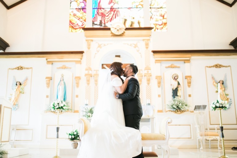 A bride and groom kiss at the altar