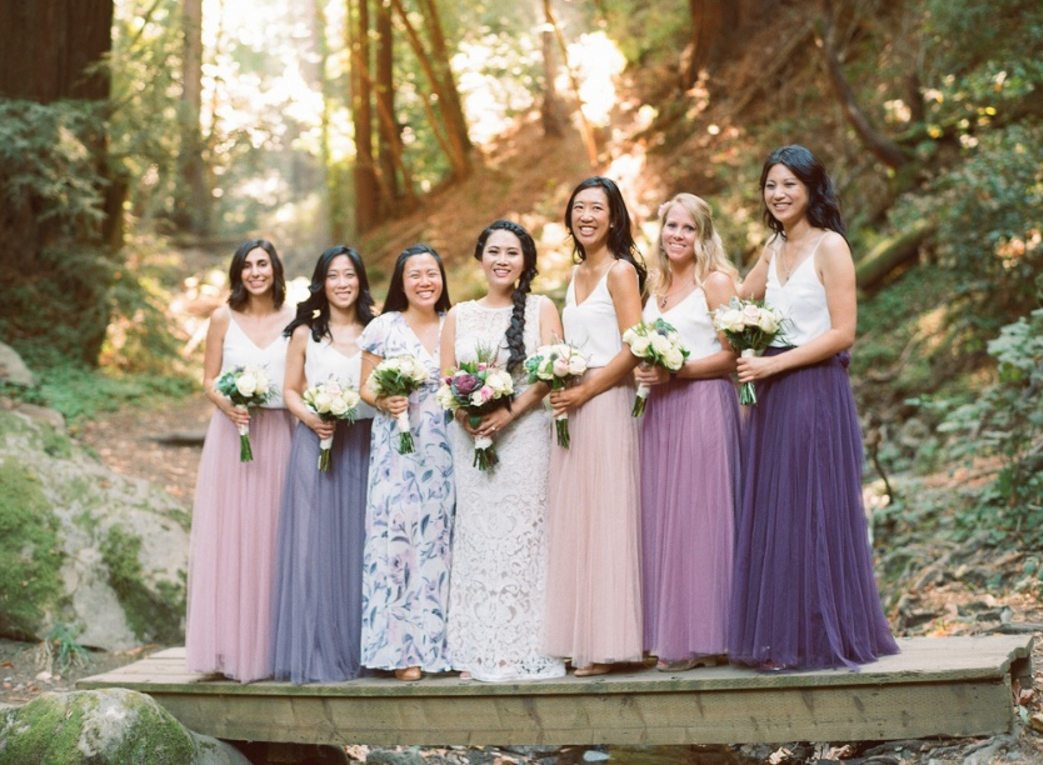 bridesmaids in mismatched skirts and tops in purple, peach and blush
