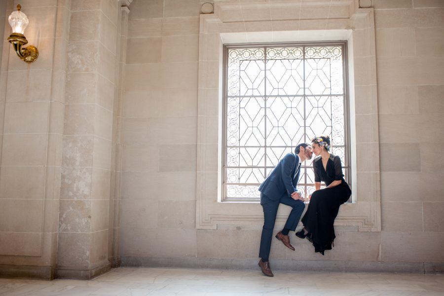 A man and woman kissing in a window frame at san francisco city hall