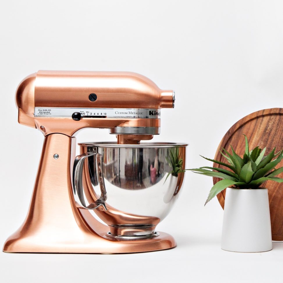 copper stand mixxer on counter next to plant and wooden board