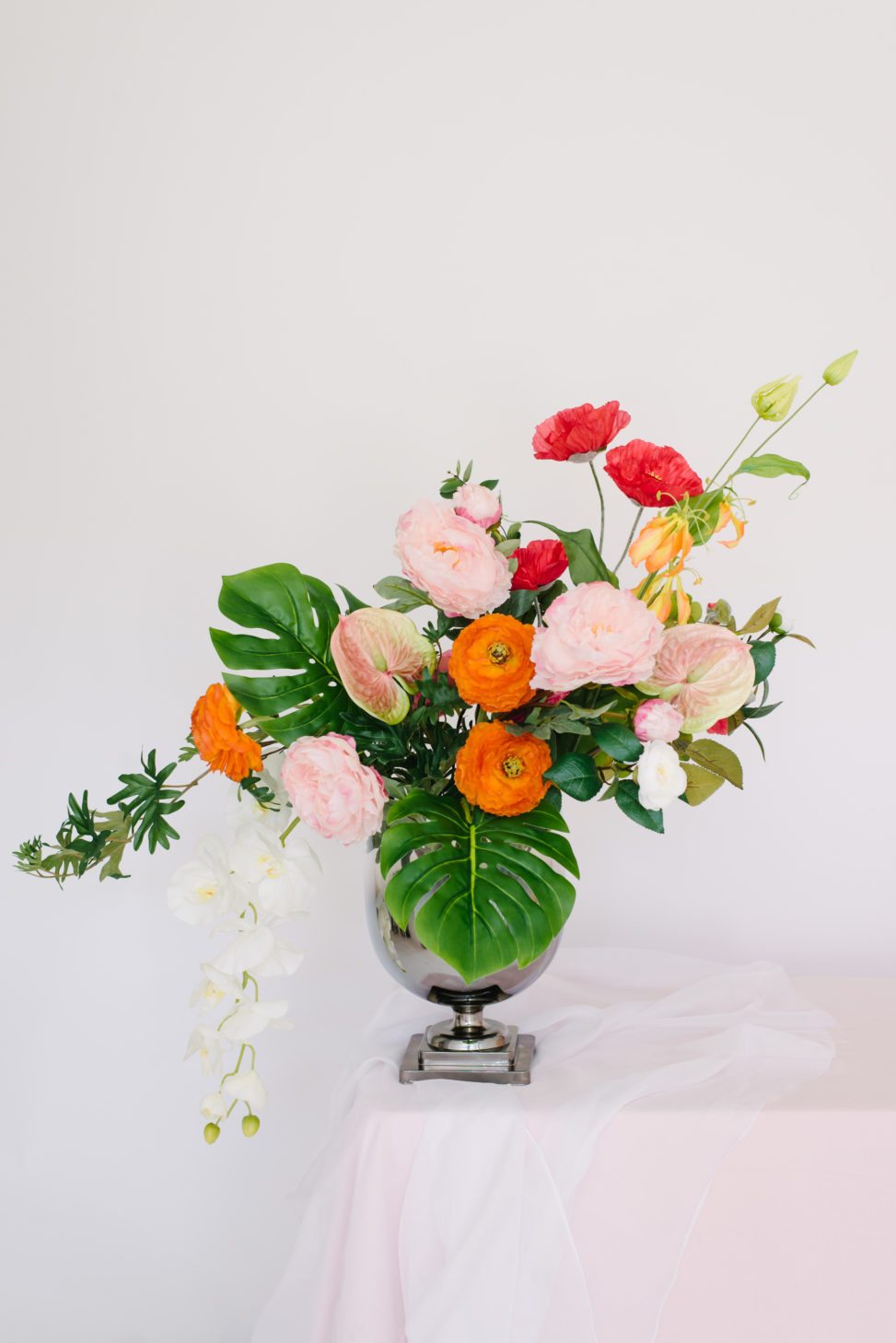 vase with fake floral red, pink, and orange bouquet that looks real on white background