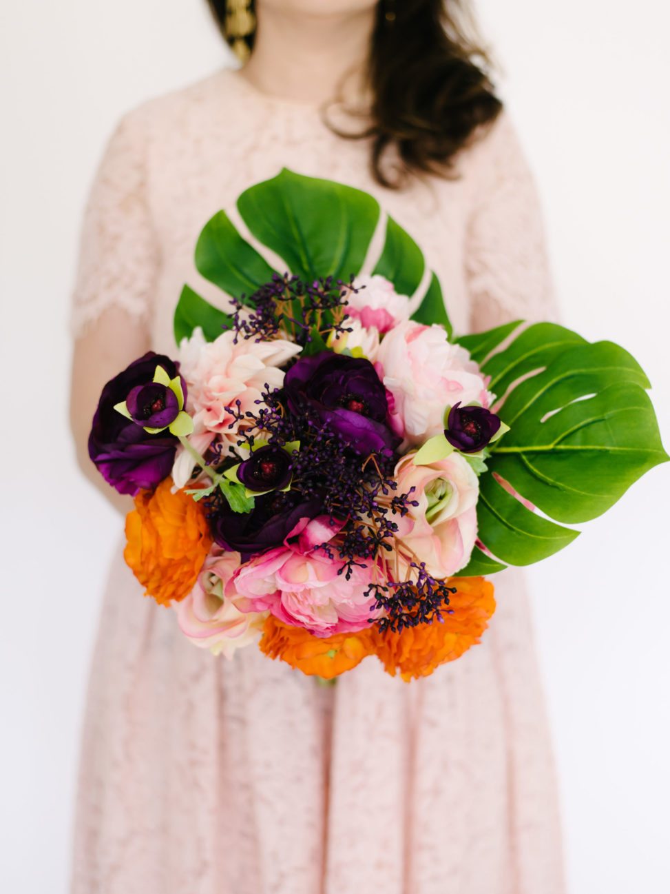 Fake flower arrangement that looks real with silk leafs and silk peonies held by woman in dress