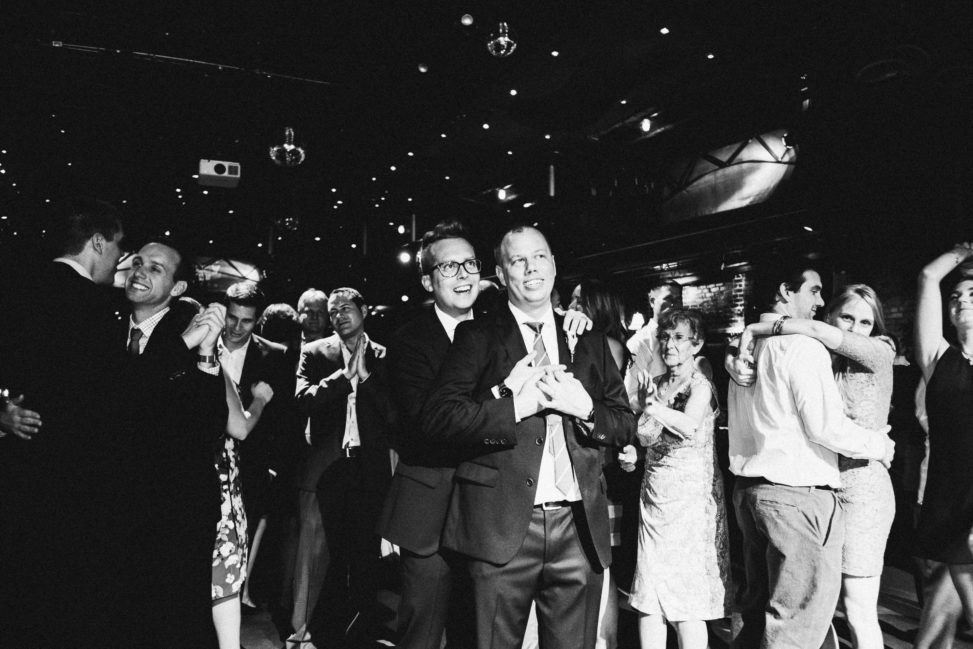 two men look on during a wedding reception