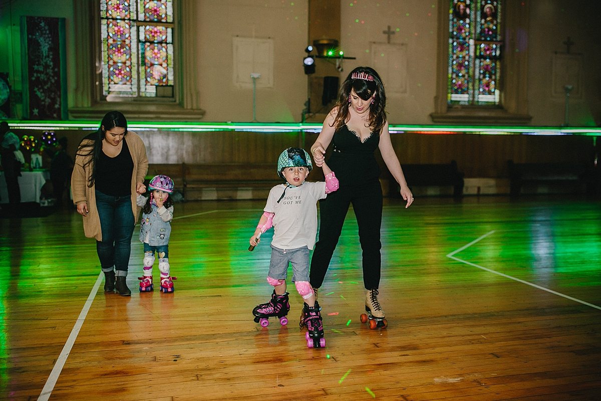 two women hold hands of children as the roller skate