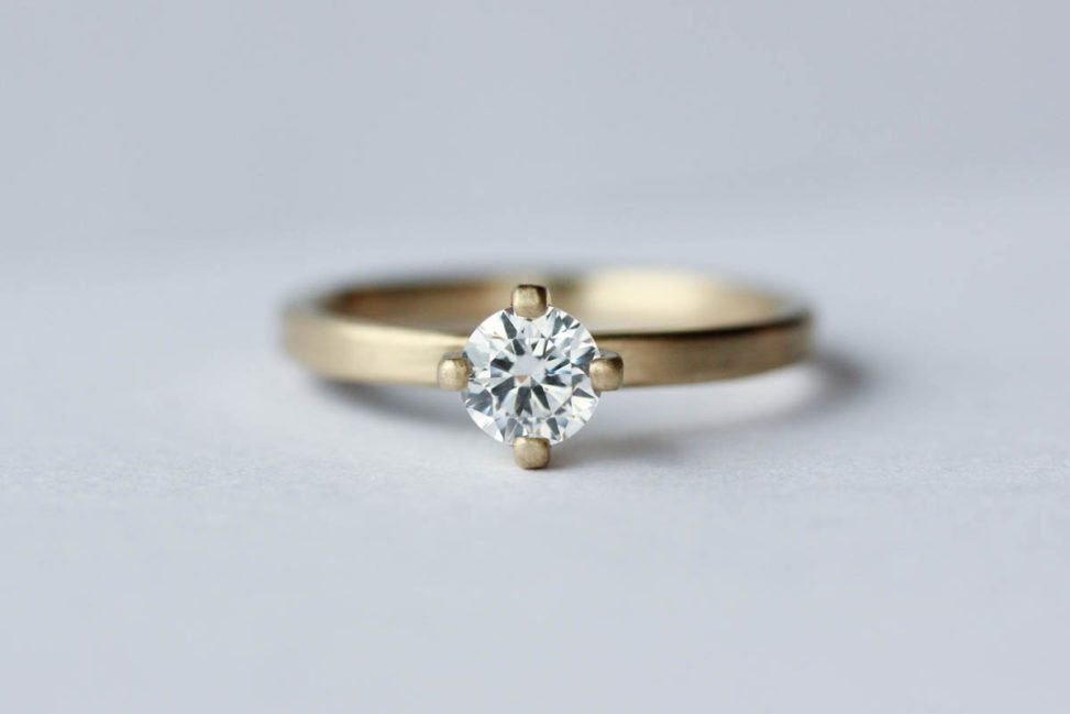 Edgeless solitaire diamond and gold ring on white