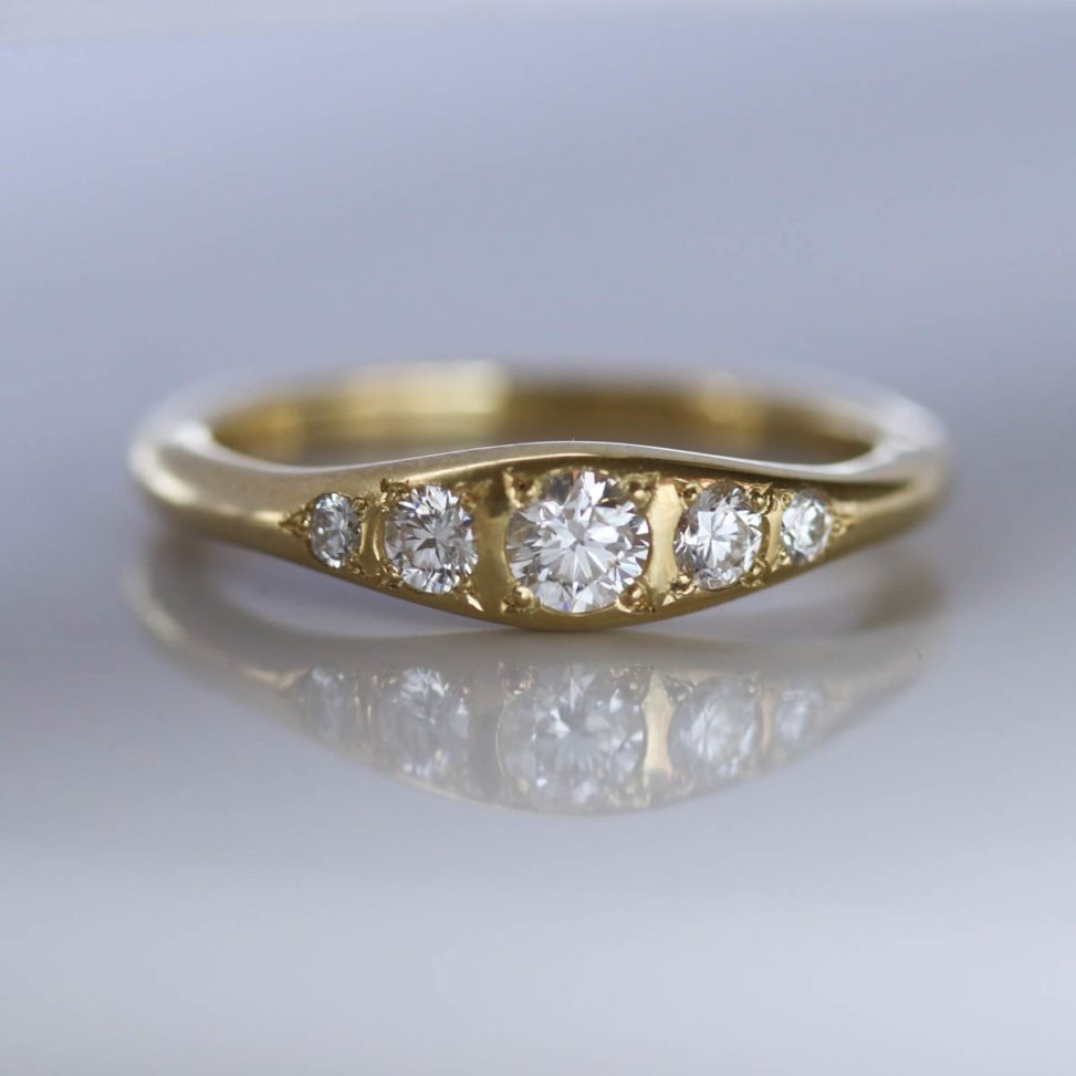 Bead-Set Five Stone Ring in diamond and gold on reflective surface