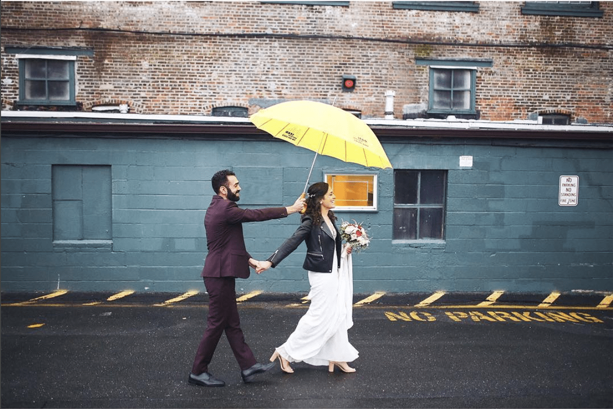 a man holds a yellow umbrella over a woman as they walk down a street