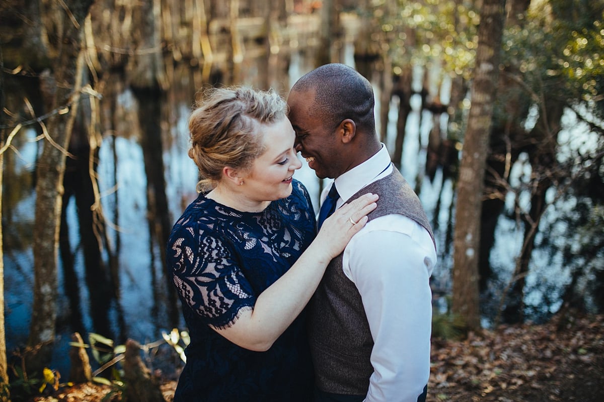 a couple embraces and smiles while standing next to a swamp